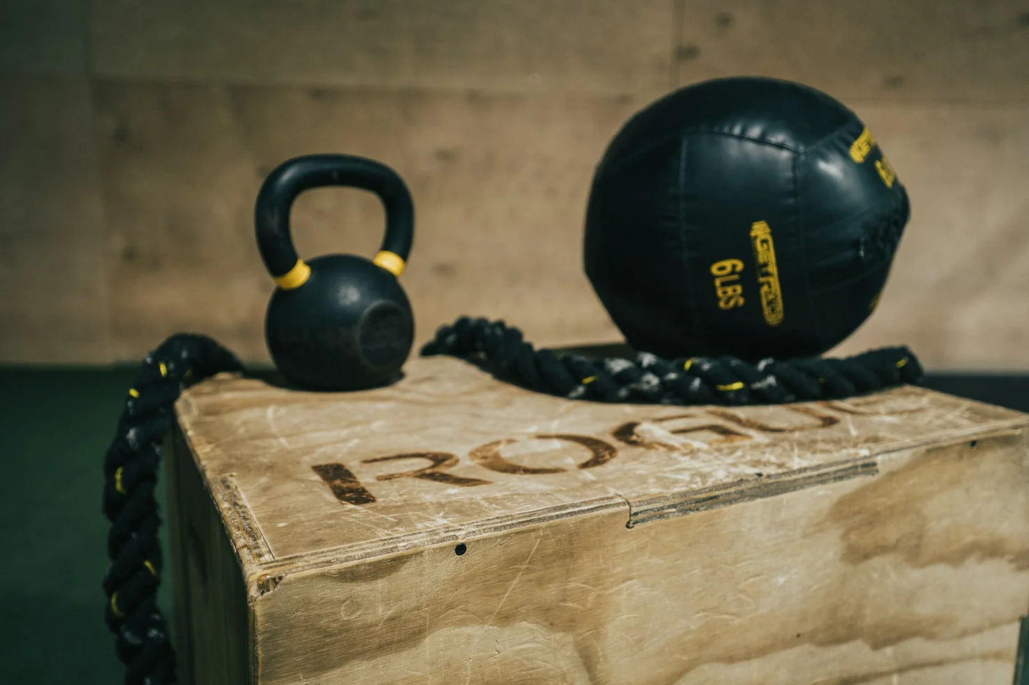 A CrossFit wooden box with a kettlebell and a medicine ball on top.