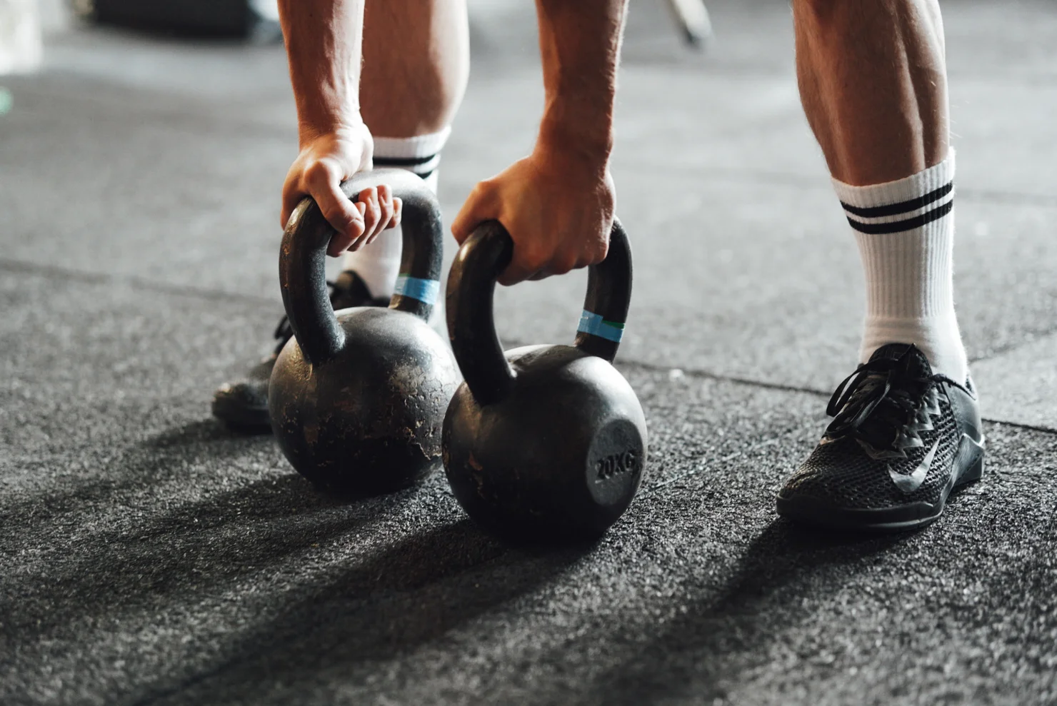 Athlet, der nach zwei Kettlebells auf dem Boden greift.