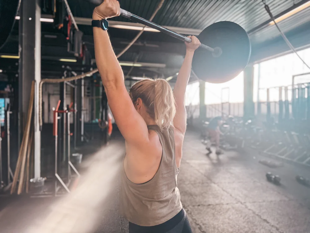 Athletin, die mit einer Langhantel Thruster macht
