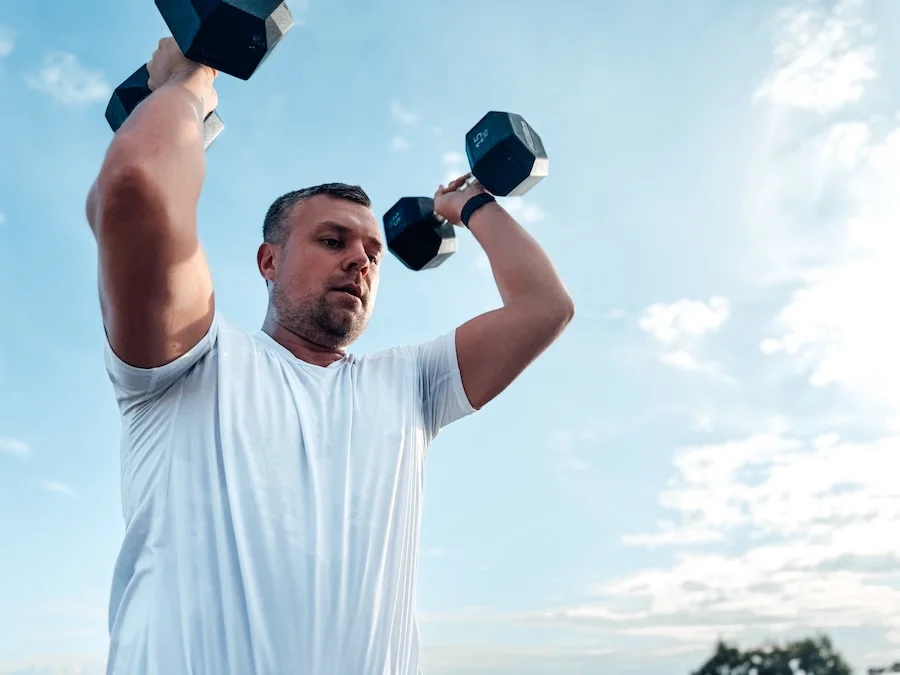 Athlete training outdoors with dumbbells