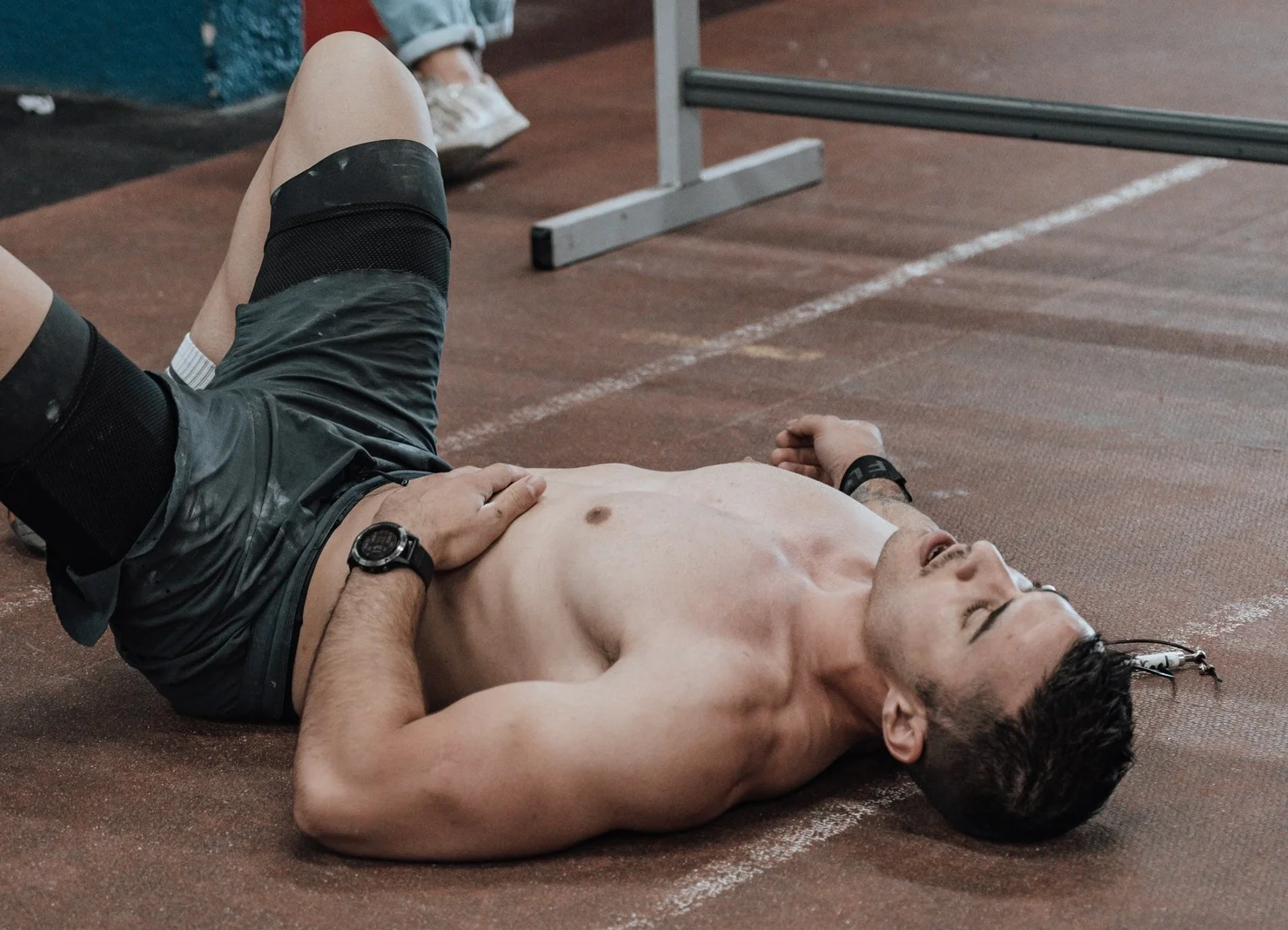 CrossFit athlete lying sweaty on the floor after a workout