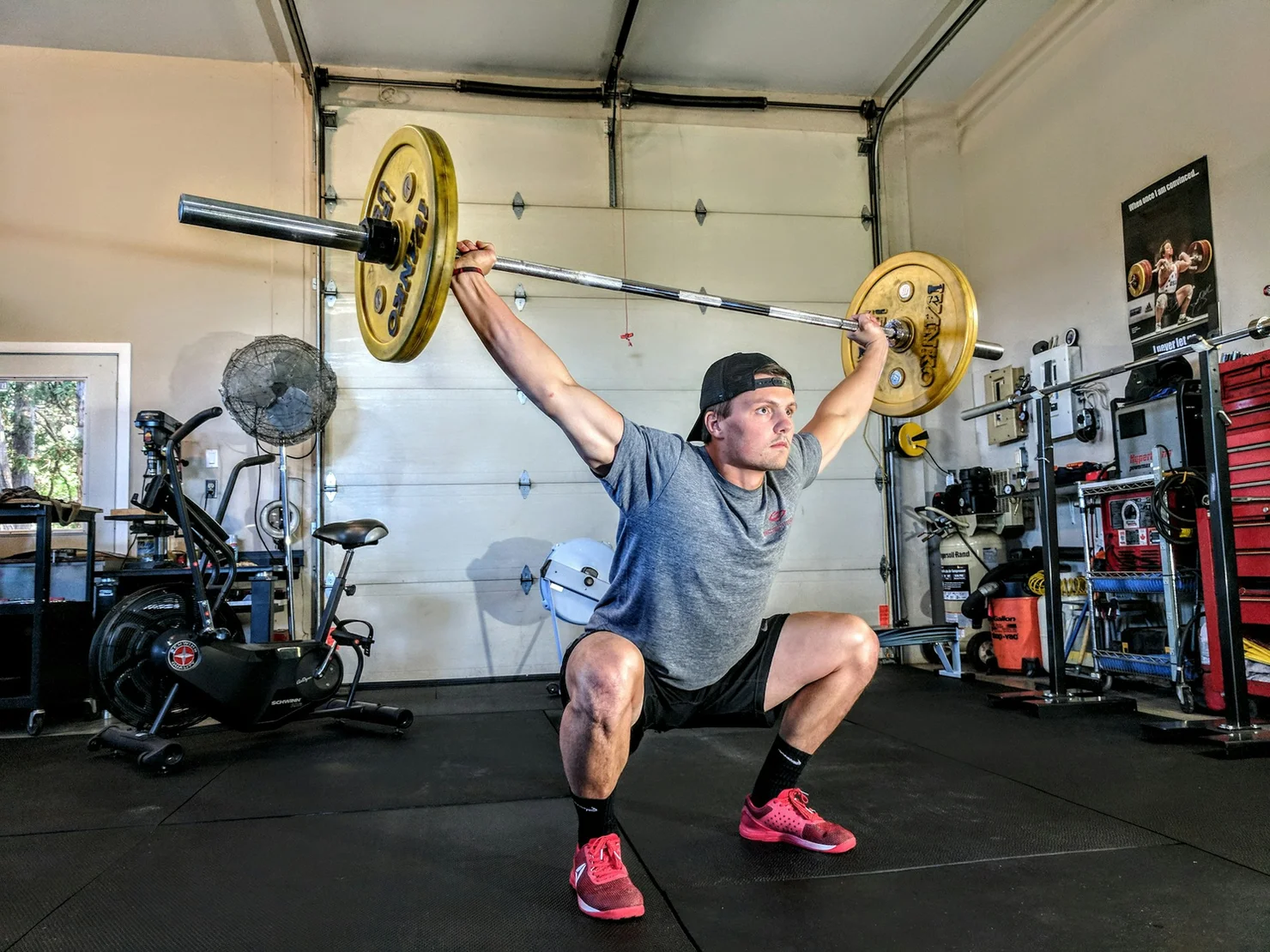 Junger Athlet, der einen Squat Snatch mit einer Langhantel macht.