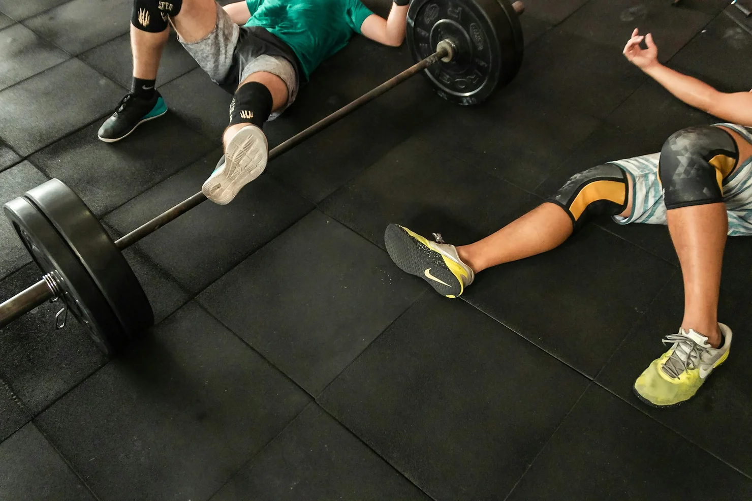 Two CrossFit athletes lying sweaty on the floor after a workout.