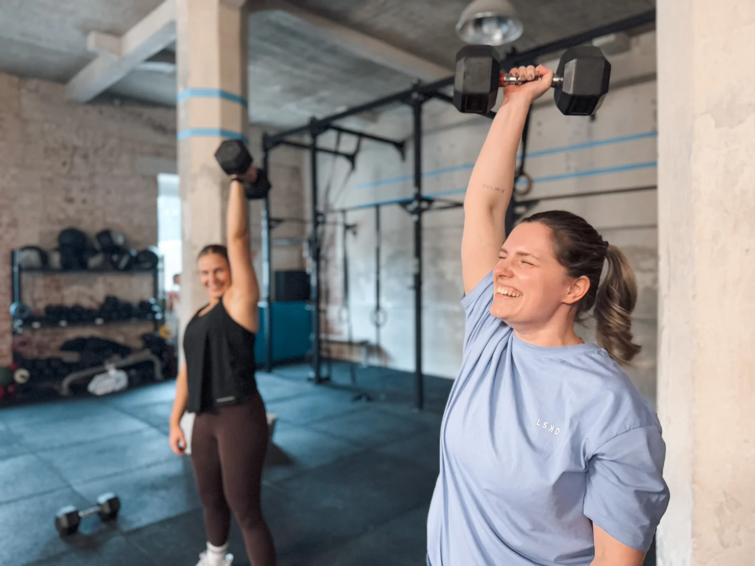 Two female athletes doing a workout with dumbbells